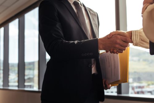 Close up of businesspeople shaking hands to conclude the meeting. Two men handshake after successful meeting in office.